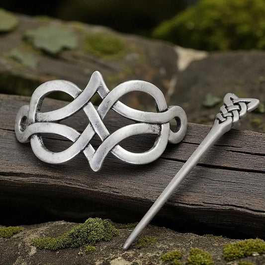 Silver Celtic knot brooch and hairpin on a wooden surface with a natural background