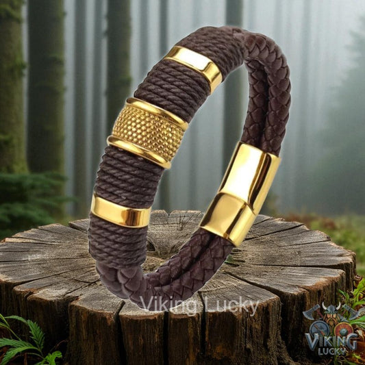 Brown braided bracelet with gold accents on a wooden stump in a forest setting, featuring 'Viking Lucky' branding.