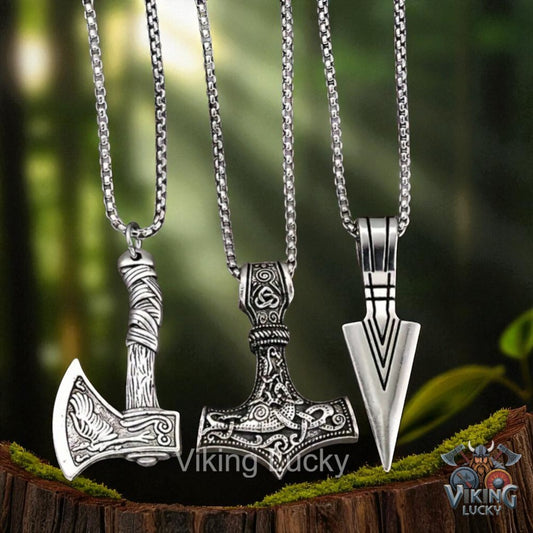 Three Viking-style pendants on chains with a blurred natural background
