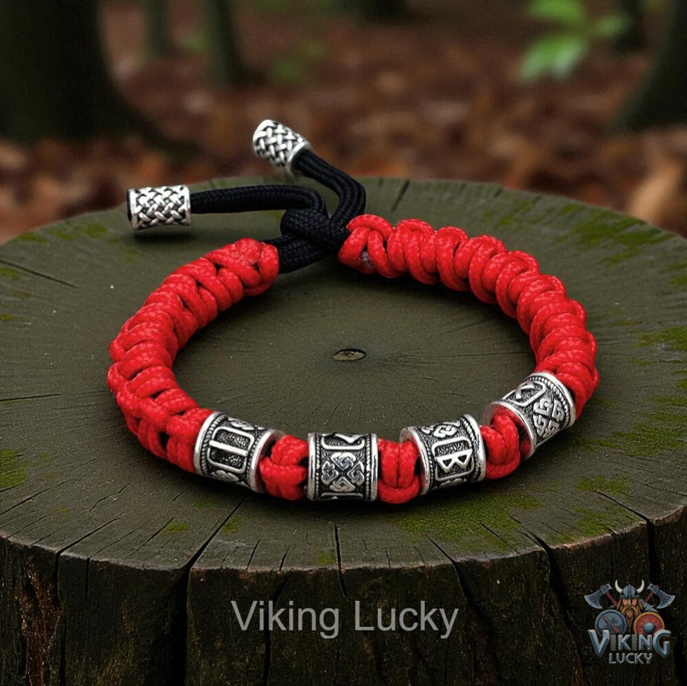 Red and black braided bracelet with silver beads on a wooden stump, branded 'Viking Lucky'.