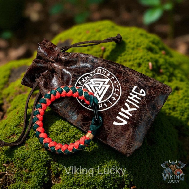 Bracelet with red and green pattern on a brown drawstring bag with 'Viking' branding on a mossy surface.