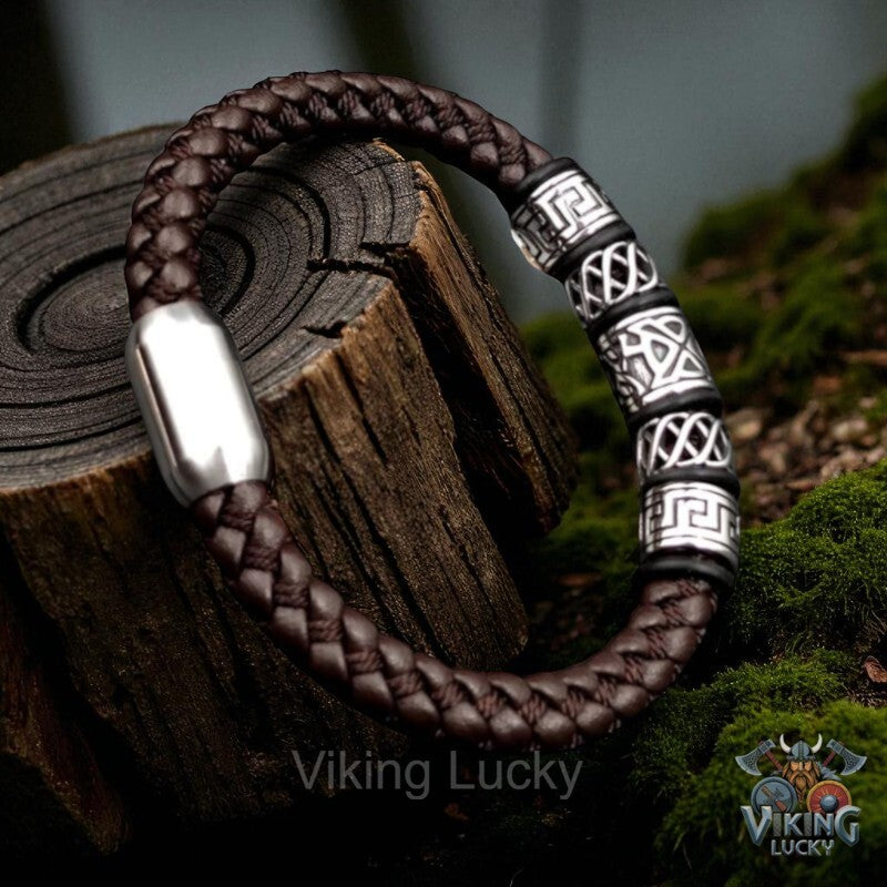 Brown braided bracelet with silver and black patterned beads on a wooden block, branded 'Viking Lucky'.