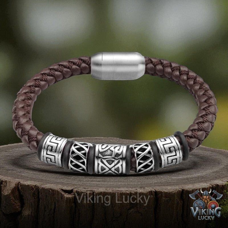 Brown braided leather bracelet with silver and black patterned beads on a wooden stump, featuring 'Viking Lucky' branding.