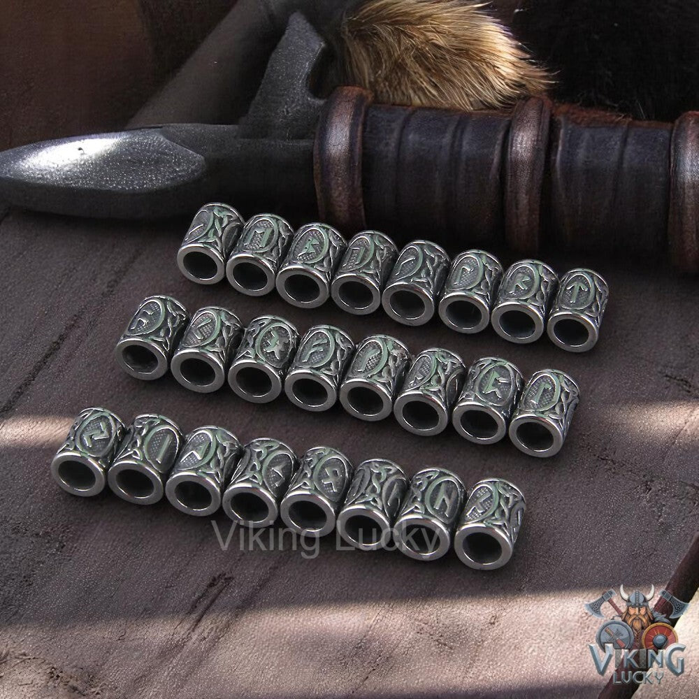 Set of silver Viking-style beads on a wooden surface with a sword in the background.