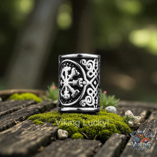Decorative black and silver container with intricate designs on a wooden surface with greenery