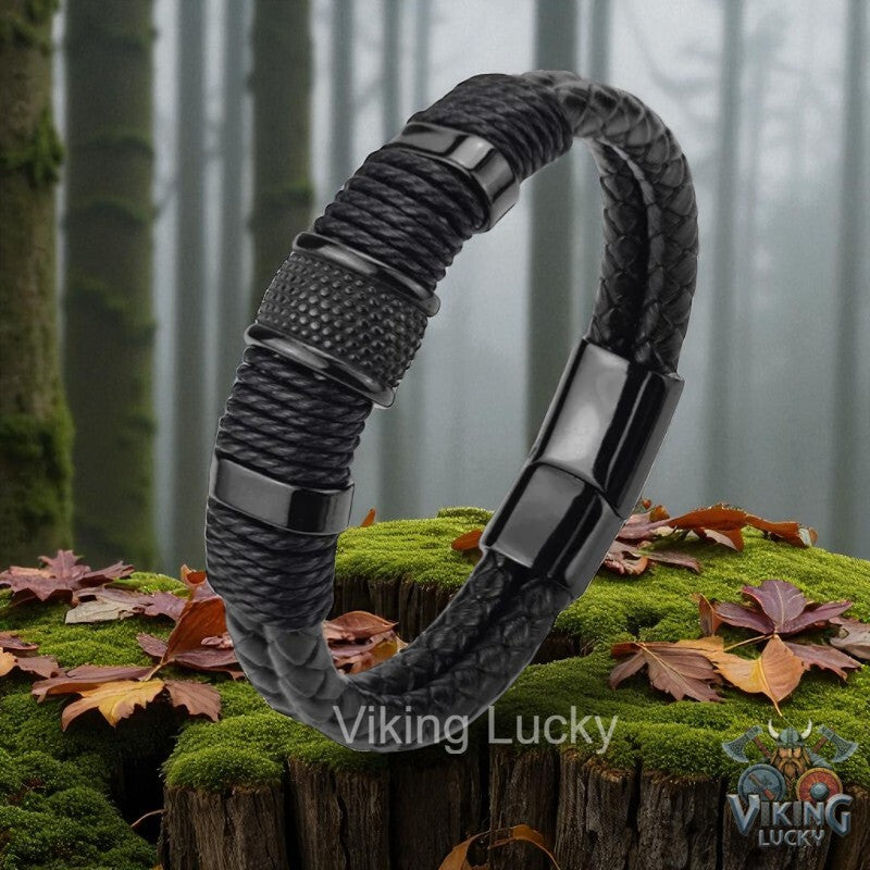 Black braided bracelet with metallic accents on a forest background, featuring the brand 'Viking Lucky'.