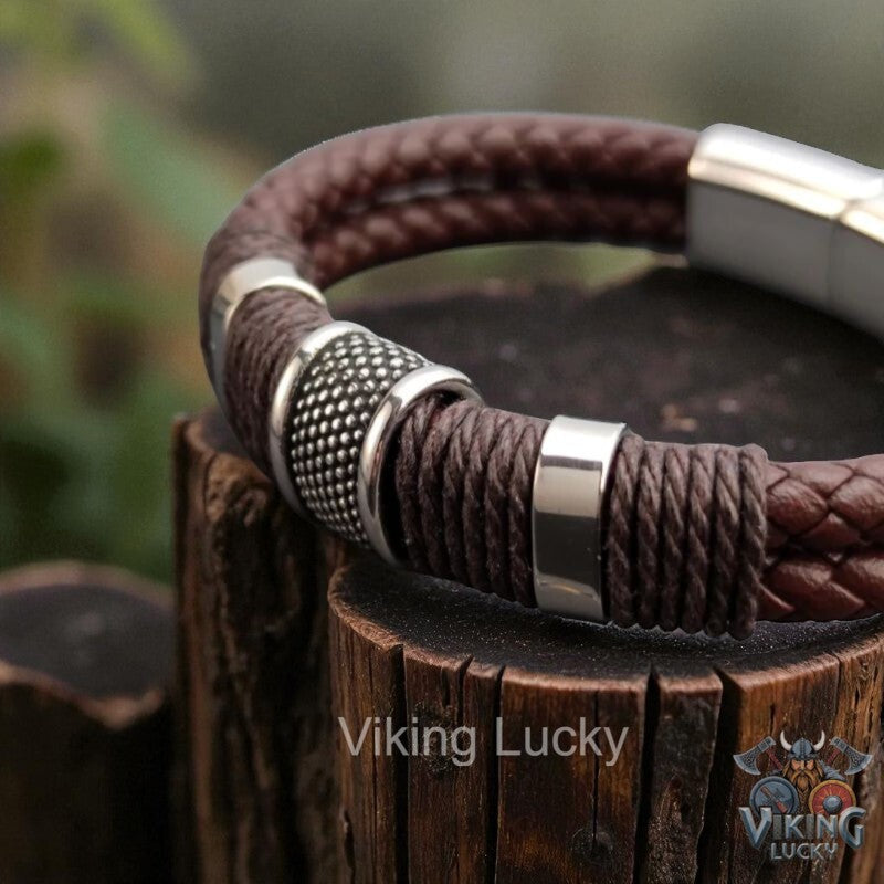 Brown braided leather bracelet with silver accents on a wooden block, branded 'Viking Lucky'.