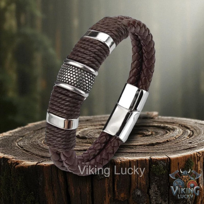 Brown braided bracelet with silver accents on a wooden stump, featuring 'Viking Lucky' branding.