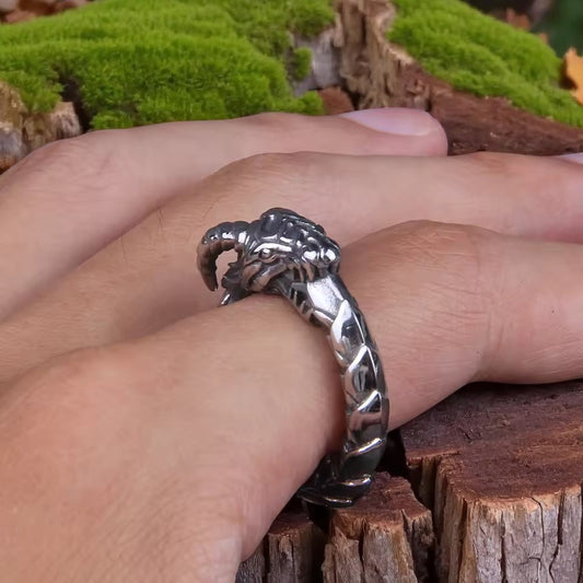 Hand trying on a dragon claw silver ring, close-up jewelry photo with natural wood and green moss background